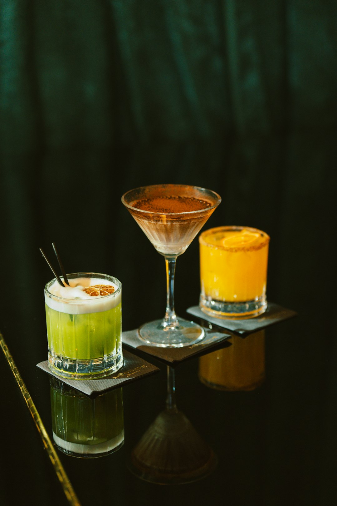 three-colorful-cocktails-arranged-on-a-dark-reflective-surface-rqiq-ybmpaa